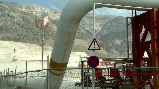 Big gas flare behind gas pipeline at Asalouyeh, Iran. Asalouyeh is the onshore location for the phased development of Iranian part of Pars gas field, the largest gas field in the world