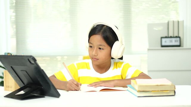 Asian girl with headphones enjoying online class on digital tablet