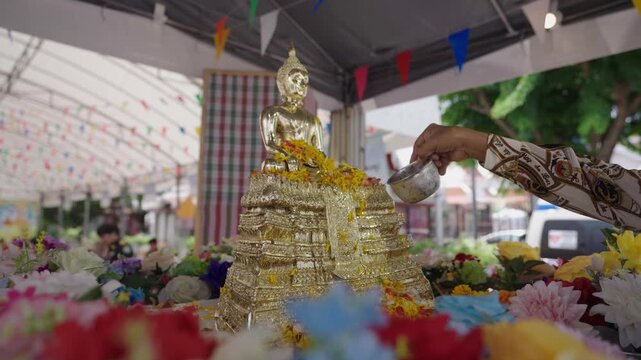 Buddhists pour scented water over a Buddha image to seek blessings during the Songkran Festival, marking the Thai New Year.