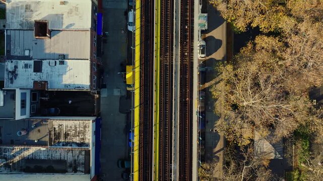 Top-down aerial drone view of elevated train tracks between buildings in Brooklyn creating strong geometric patterns and symmetry, filmed in ProRes 422HQ.