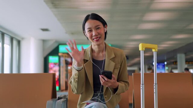 Waving goodbye after a successful morning routine, a smiling Asian woman traveler is ready for her departure. Efficient morning routine at the airport. Travel-ready concept.