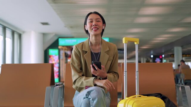 Waving goodbye after a successful morning routine, a smiling Asian woman traveler is ready for her departure. Efficient morning routine at the airport. Travel-ready concept.