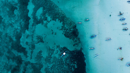 Top-down aerial view of traditional outrigger boats anchored on a vibrant coral reef in turquoise tropical waters, relax chill meditative holiday travel destination concept  © Michele