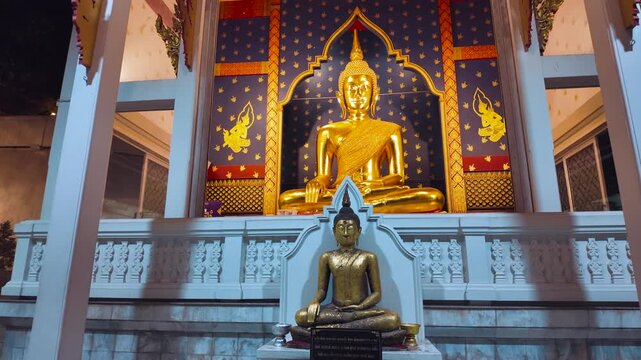 Golden Buddha statue inside Wat Saket temple with ornate interior, Lit gold Buddhism shrine with blue wall decoration in Thai temple in Bangkok 4k