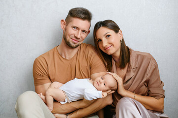 Fototapeta premium Parents Sitting And Holding Baby At Home