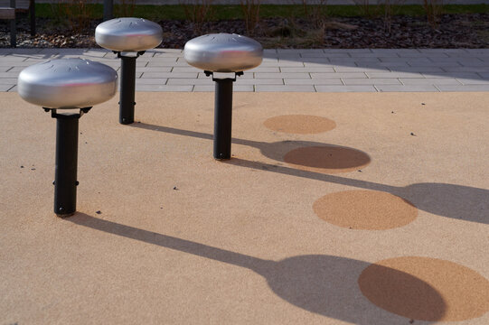 Metal tongue drums standing on playground surface.