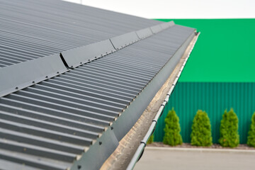 Corrugated metal roof a modern building with gutter on green background. © Andrey
