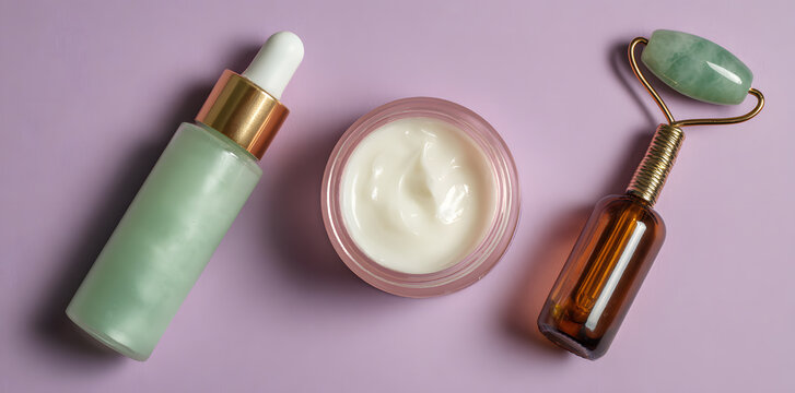 Skincare set with cream, bottle and jade roller on pastel background. Beauty routine concept with minimal cosmetic products and spa tools.