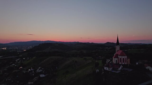 Gorca - Marijina cerkev v Malečniku , Slovenia - drone view on the church, river Drava and Maribor during sunset
