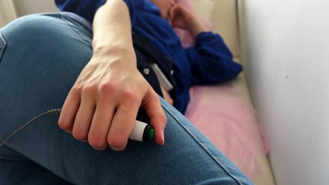 Pregnant woman in a clinic lying on a medical couch and undergoing a cardiotocography nonstress test, pressing a button every time the baby moves to check the fetal heartbeat