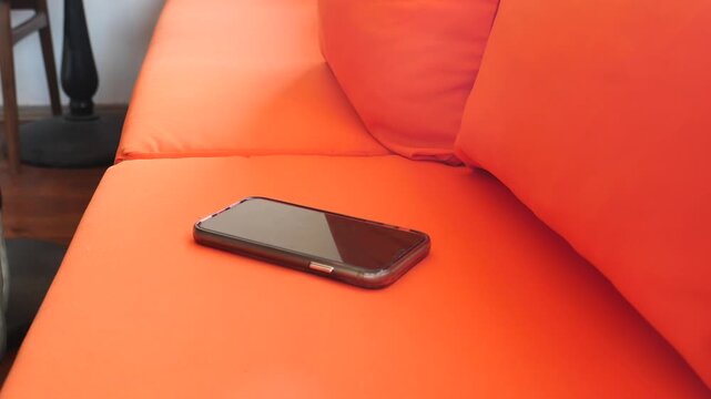 Phone placed on orange couch in living room setting. lost phone concept 