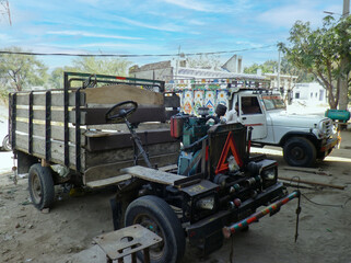 Fototapeta premium Rusty flatbed trailer beside white pickup truck