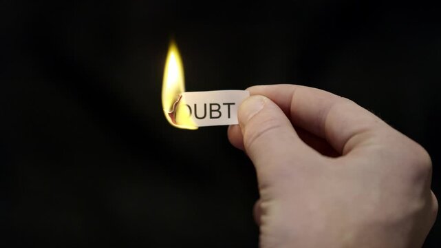 Burning Away Doubt - Hand Setting Fire to Paper note Marked &ldquo;DOUBT&rdquo;, Powerful Release of Criticism, Guilt and Shame, Dark Cinematic Close-Up. Mental health, therapy