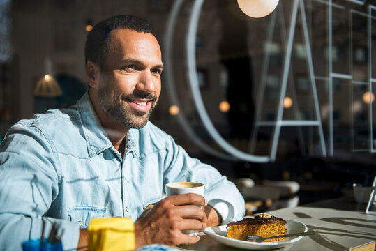Portrait of smiling man enjoying coffee and cake at caf� table