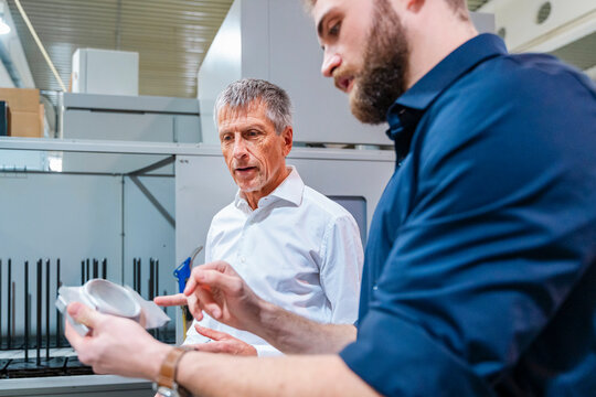 Two men discussing a machine system in a production hall