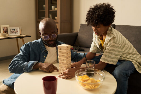 Father and son playing board game and having snacks at home