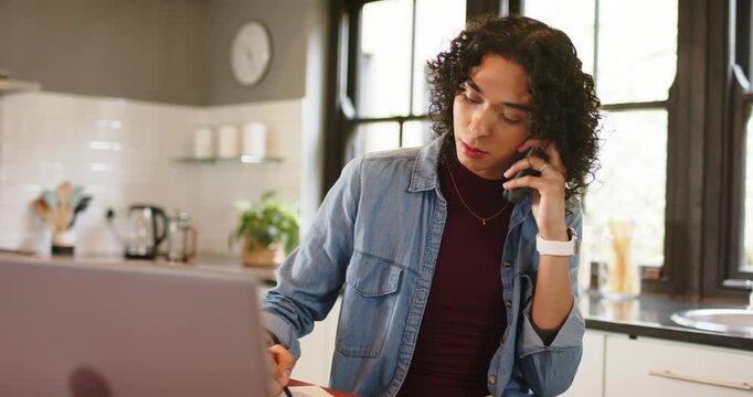 Non-binary person placing laptop, answering call, jotting in notebook and smiling at kitchen table