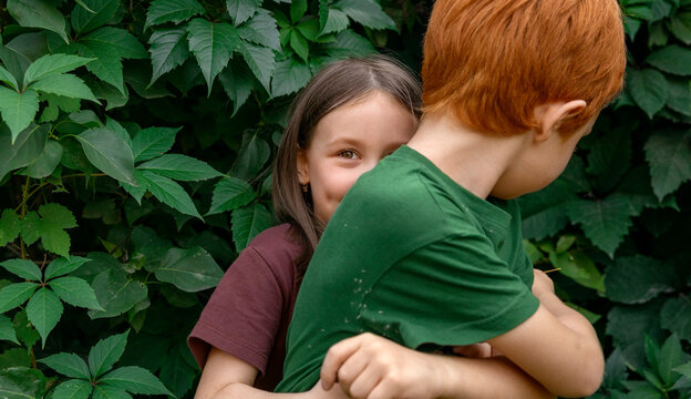 Happy children hugging in garden with vine leaves in background