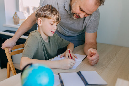 Father helping son with homework at home for joyful learning