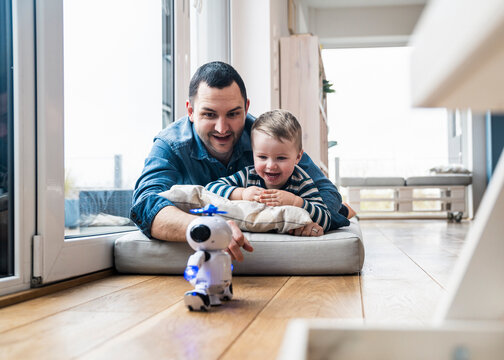 Father and son playing with robot toy together at home