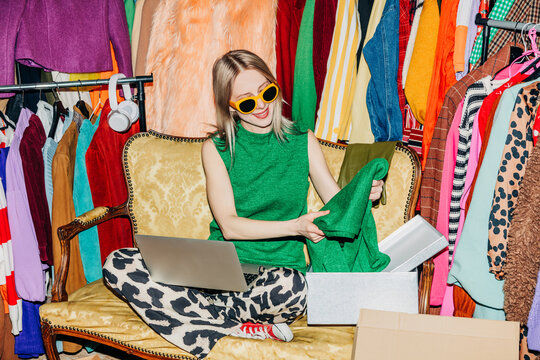Fashion reseller working on laptop packing clothes for online sale