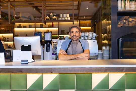 Bartender smiling while leaning on counter in modern cafe