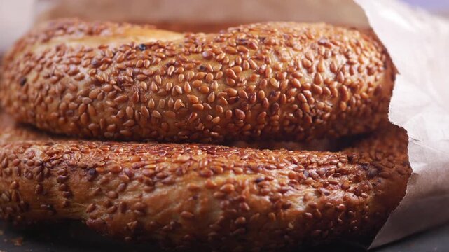 Close up shot of fresh bagels covered in sesame seeds, paper bag, bakery