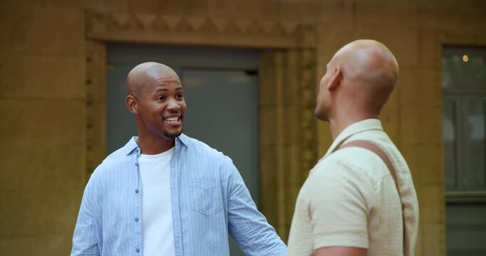 African American men greeting on meeting, chatting outside stone door in blue shirt and brown bag