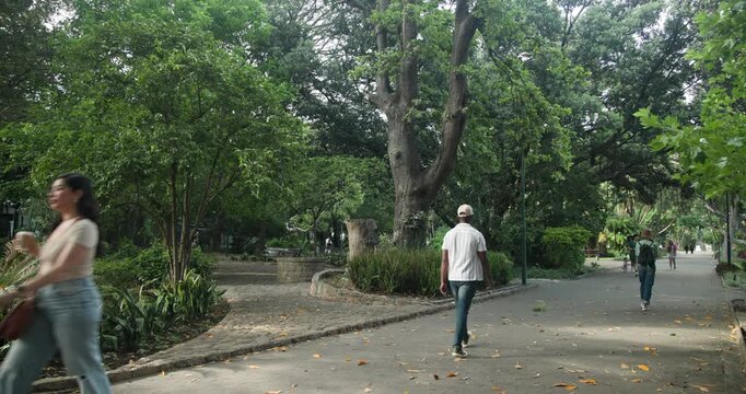 Diverse pedestrians walking along paved park path, entering from sides, using path, guiding bicycle