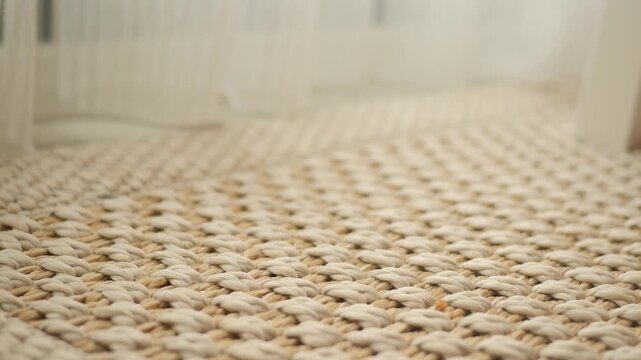 A close up view of the carpet shows light beige and off white colored patterns that are woven together to create a textured surface