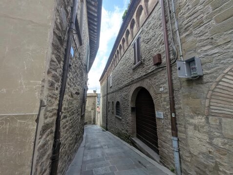 Vicolo storico in pietra con edifici tradizionali e porta ad arco, atmosfera tranquilla di un borgo europeo antico