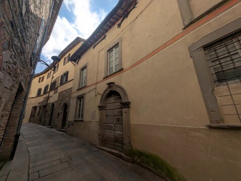 Vicolo storico in pietra con edifici tradizionali e porta ad arco, atmosfera tranquilla di un borgo europeo antico