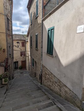 Scalinata in pietra che scende tra edifici storici con finestre e persiane, atmosfera autentica di un borgo europeo antico