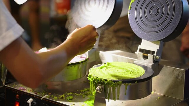 Street food vendor cooking traditional Thai fresh coconut rolls Thong Muan Sot with taro and pandan flavors at a night market in Thailand.