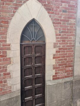 Porta lignea ad arco in stile gotico incastonata in una facciata in mattoni e pietra. Dettagli artigianali e atmosfera storica elegante