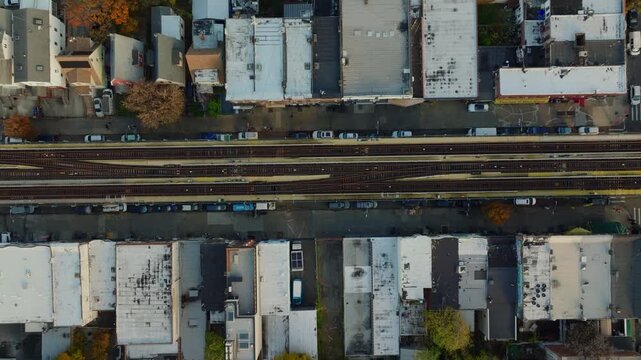 Top-down aerial drone view of elevated train tracks between buildings in Brooklyn creating strong geometric patterns and symmetry, filmed in ProRes 422HQ.