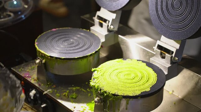 Street food vendor cooking traditional Thai fresh coconut rolls Thong Muan Sot with taro and pandan flavors at a night market in Thailand.