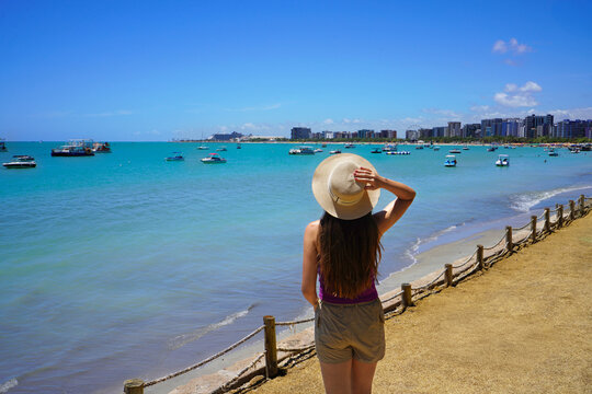 Tourism in Maceio, Brazil. Beautiful young woman looking towards the natural swimming pools of Pajucara, Maceio, Brazil.