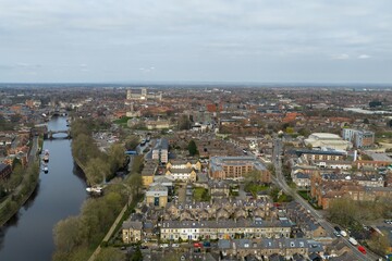 Obraz premium Aerial view of York city centre with River Ouse bridges historic buildings and York Minster visible in the distance with urban housing and streets captured from above in early spring time