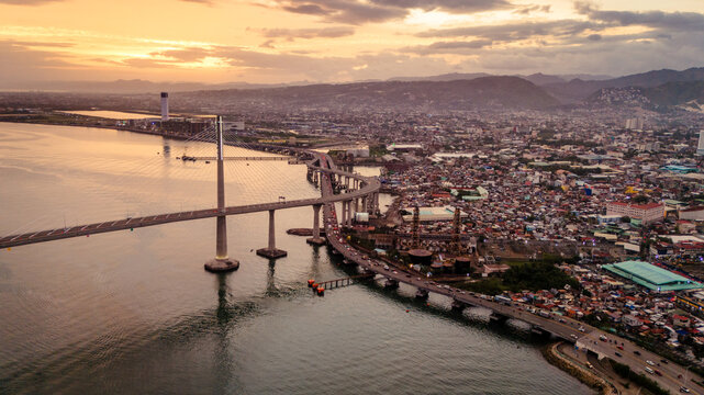 Cinematic aerial drone shot of Cebu City at sunset, showcasing the urban skyline as city lights begin to glow at dusk