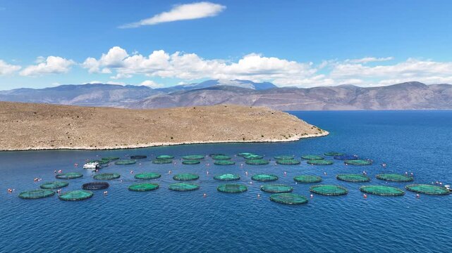 Aerial drone cinematic video of aquaculture fish farm cages producing sea breem and sea bass in deep blue Mediterranean sea