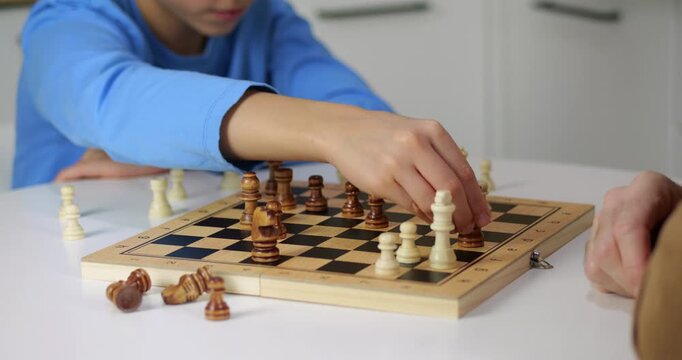 Close up of chess pieces on board. Defocused players play chess game at home. Wooden figures in chess game match. Strategy and intelligence concept video.