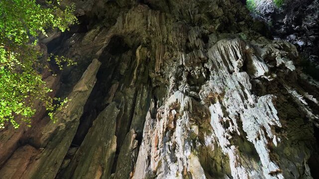 Natural skylight illuminating the interior limestone formations and lush green plants within Khao Chang Lon Cave in Songkhla Southern Thailand.