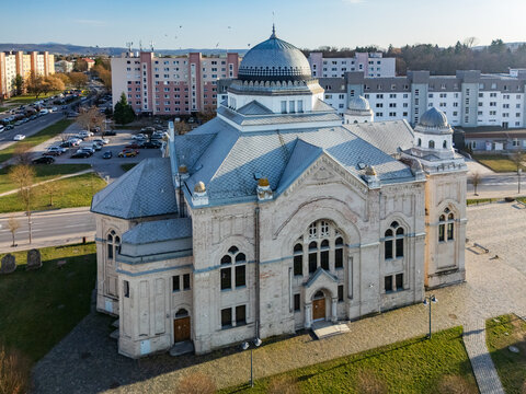 Aerial view of the grand synagogue stands in stark relief against the urban backdrop, its dome gleaming under the sunlight, Lucenec, Banska Bystrica Region, Slovakia.