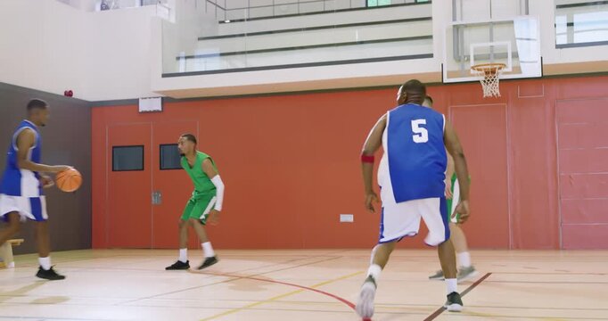 Intercepting ball male in blue jersey dribbling toward hoop to score in school gym