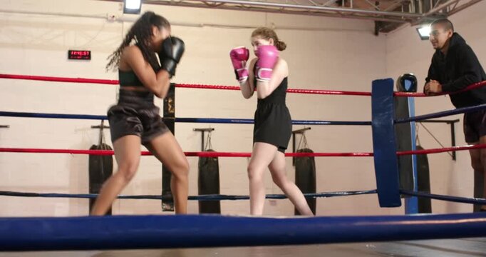 Timer signaling start African American boxer and teenage partner trading gloved jabs in ring
