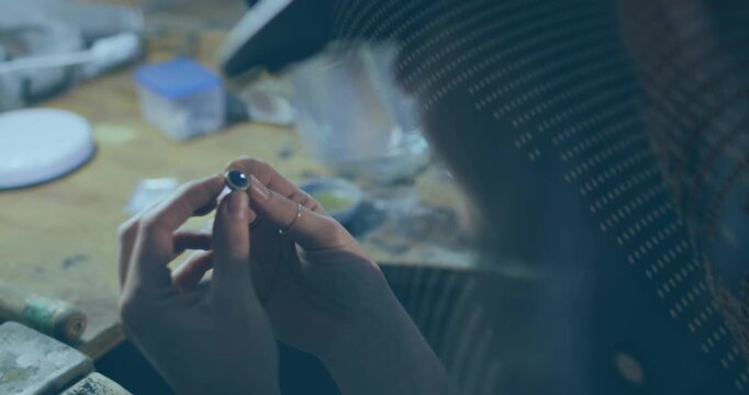 Jeweler rotating ring, bringing ring close and inspecting stone seat under dotted magnifier overlay
