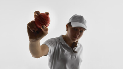 Fototapeta premium Female cricket player holding cricket ball toward camera isolated on white background. Concept of sports advertising banners, promotional campaigns, brand messaging, copy space design.