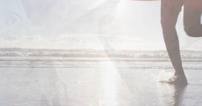 Right-edge foot entering, revealing surfing couple running to surf, boards reflecting glare