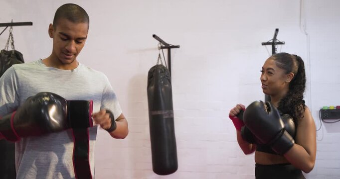 Two training partners adjusting gloves and wraps before shadow sparring on pink mats at boxing gym